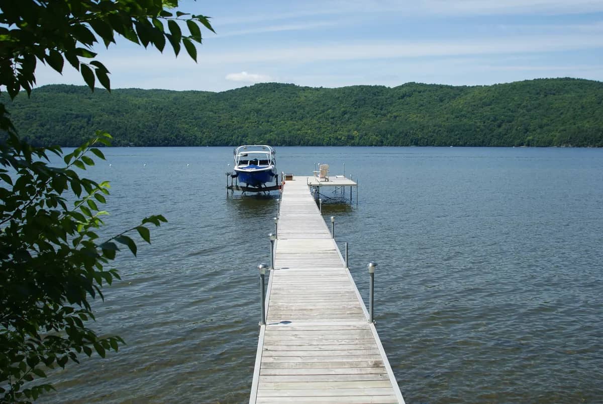 Bateau soulevé sur un élévateur au bout d’un quai, bord de lac boisé