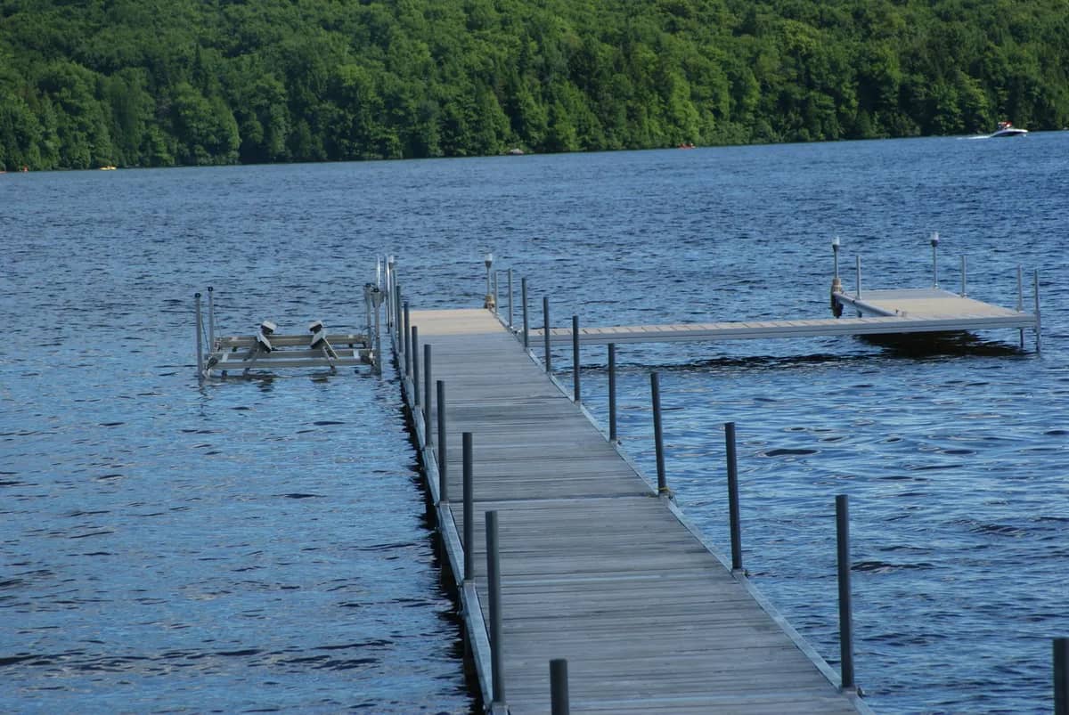 Quai avec petit élévateur sur un lac bleu bordé de forêt